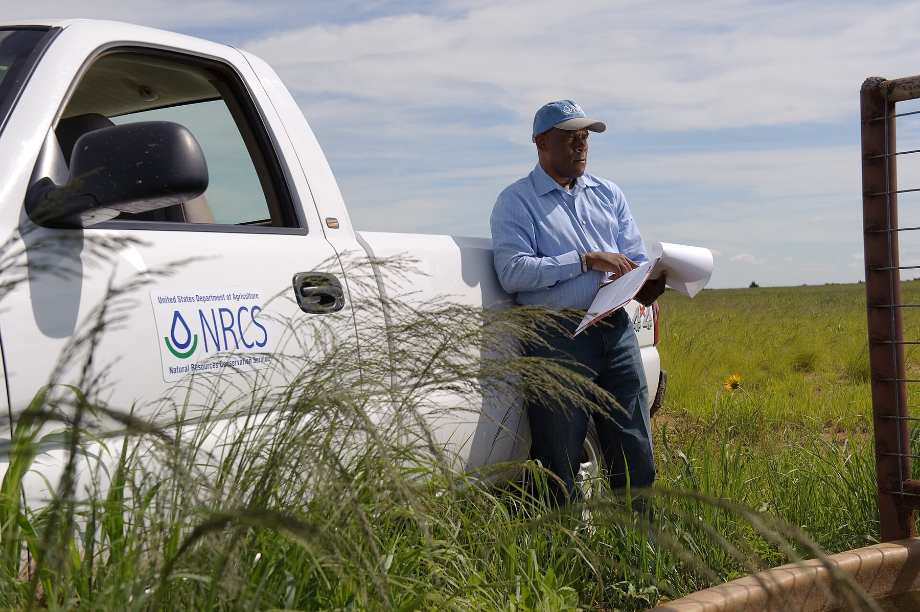 A conservationist checks a field status report beside a service truck.