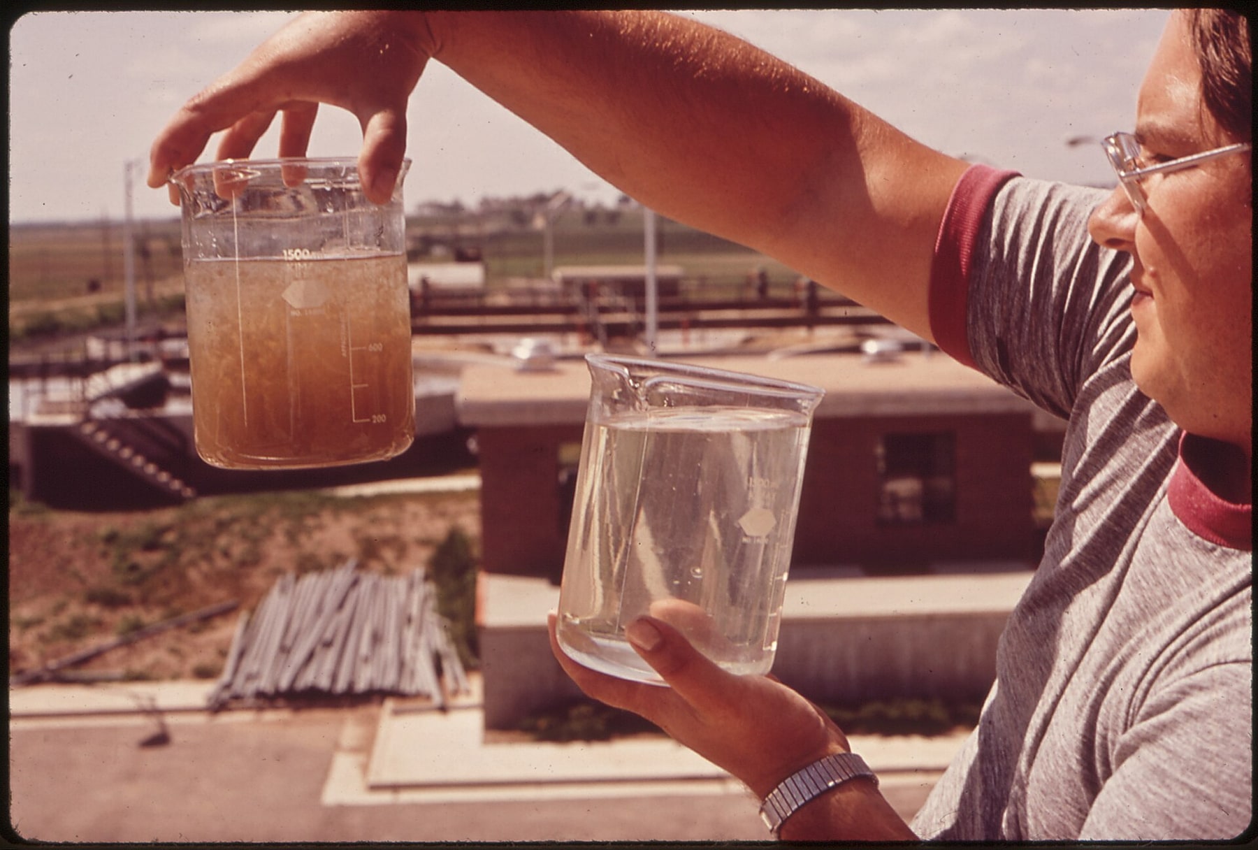 A technician compares cloudy incoming water with clear treated water.