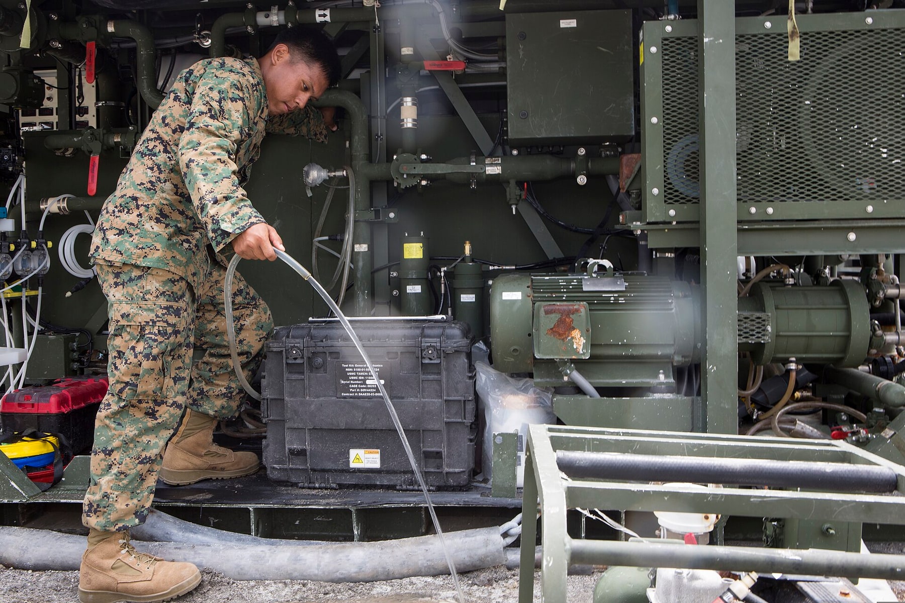 A water technician services pumps and hoses inside a mobile purification unit.