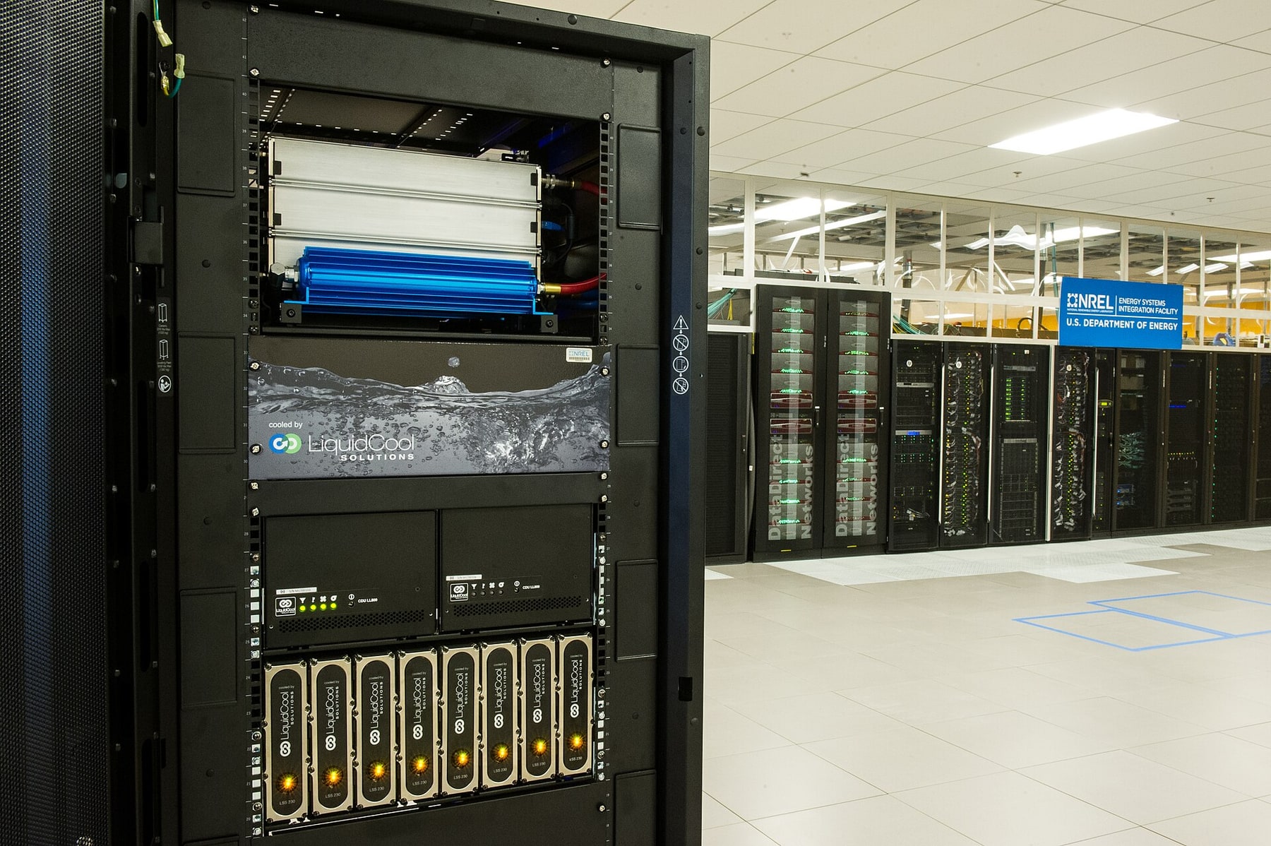 An open NREL server rack exposes a blue liquid-cooling unit and coolant lines.