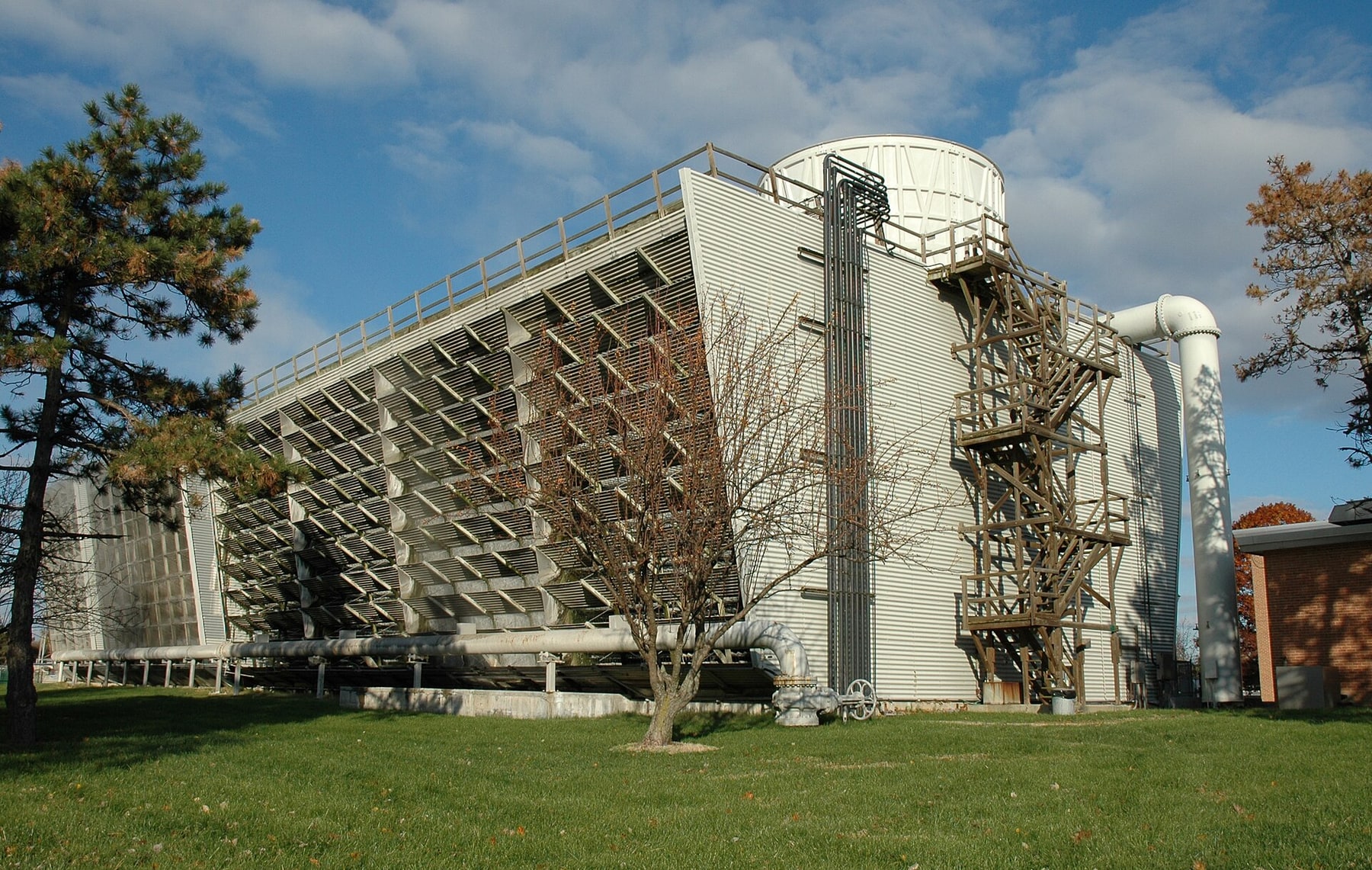A large louvered cooling structure and exposed pipes stand outside a NIST laboratory.