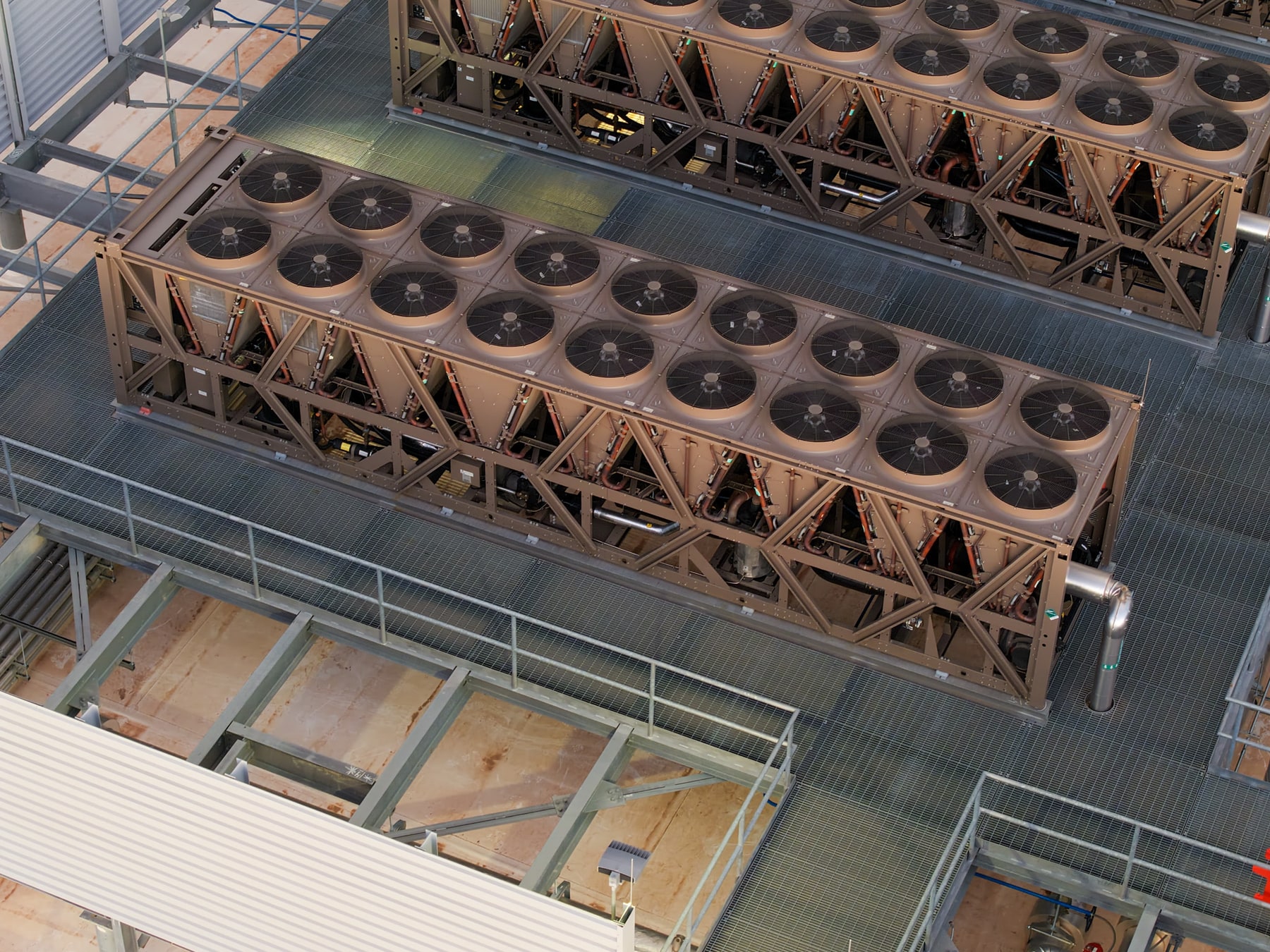 Rows of rooftop cooling units and fans are viewed from above.