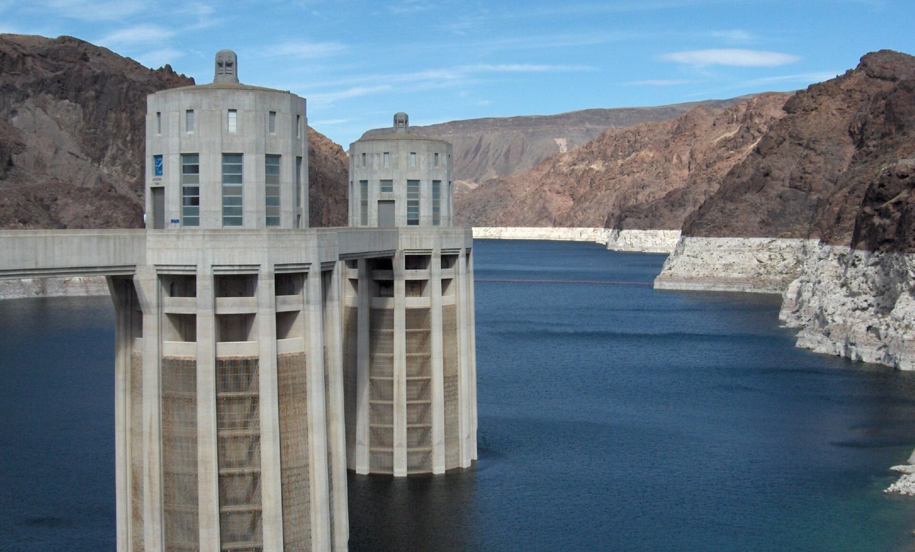 Two intake towers rise from Lake Mead beside the reservoir's exposed pale shoreline.